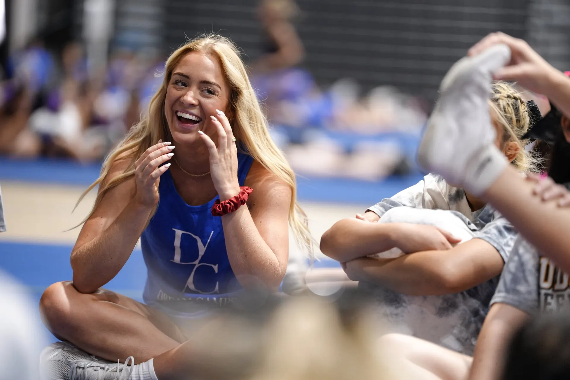 A coach laughing with athletes on the mat